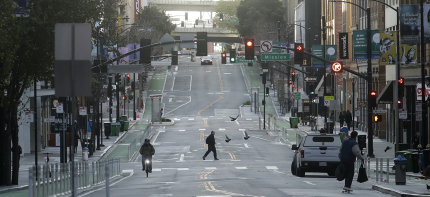 A man crosses a nearly empty street in San Francisco on March 17, 2020. 