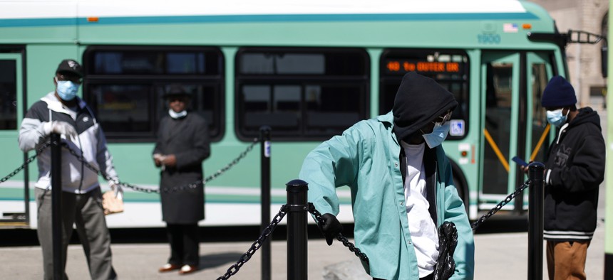 People wait for the bus in Detroit. The city, which has been a coronavirus hotspot, is also one of the top U.S. cities for rates of hypertension, a comorbidity of coronavirus.