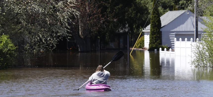 A kayaker paddles out to check on a residence as the Tittabawassee River overflows, Wednesday, May 20, 2020, in Midland, Mich. 