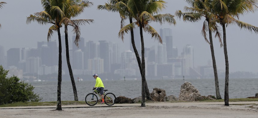 The Miami skyline is shrouded in clouds that would become Tropical Cyclone Arthur as a cyclist rides along Biscayne Bay at Matheson Hammock Park, Friday, May 15, 2020, in Miami.