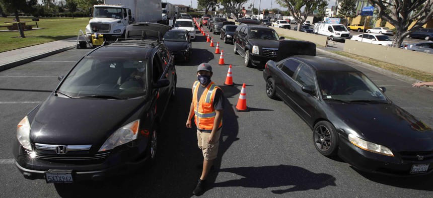 Cars line up at a food distribution center Friday, May 15, 2020, in Compton, Calif. 