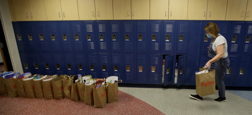 LuAnn Duval places bags of her students' belongings outside her second grade classroom at Walnut Grove Elementary school on May 12, 2020, in Olathe, Kansas.