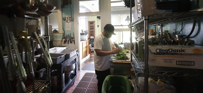 Jesus Cruz, prep cook at Blue Plate, covers his face with a mask while working in the kitchen at the San Francisco restaurant, during the coronavirus outbreak Thursday, May 14, 2020. 