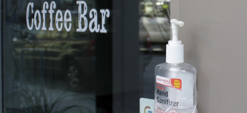 A jar of hand sanitizer is shown taped to the door handle of a coffee shop in downtown Portland, Ore., Monday, March 16, 2020. 
