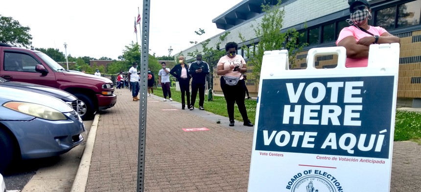 Voters wear masks and maintain distance from one another while they wait in line to cast ballots at the Hillcrest Recreation Center in Washington, D.C. on Tuesday June 2, 2020.