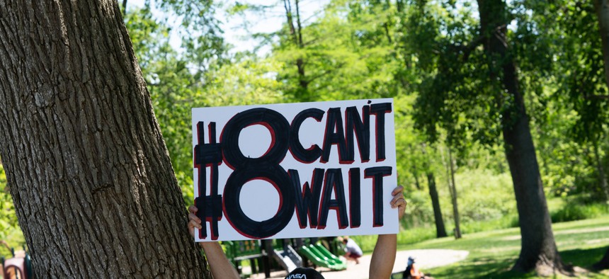 A protester in Michigan holds up a sign for the #8CantWait campaign.