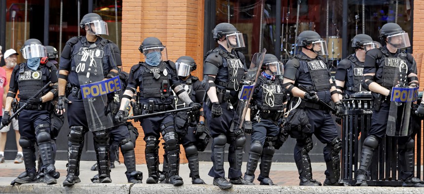 In this June 4, 2020, file photo, Metro Police officers watch as marchers in a protest pass through downtown Nashville, Tenn.