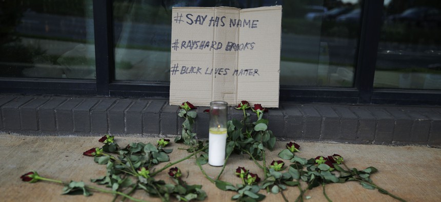 A memorial with roses and a sign is displayed near a sidewalk on Saturday, June 13, 2020, near the Atlanta Wendy's restaurant where Rayshard Brooks was fatally shot by police late Friday.