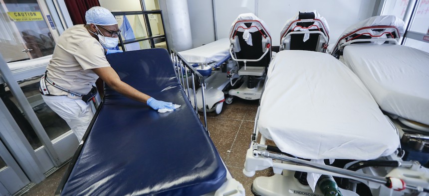 A medical worker wearing personal protective equipment cleans gurneys in the emergency department intake area at NYC Health + Hospitals Metropolitan, Wednesday, May 27, 2020, in New York. (AP Photo/John Minchillo)