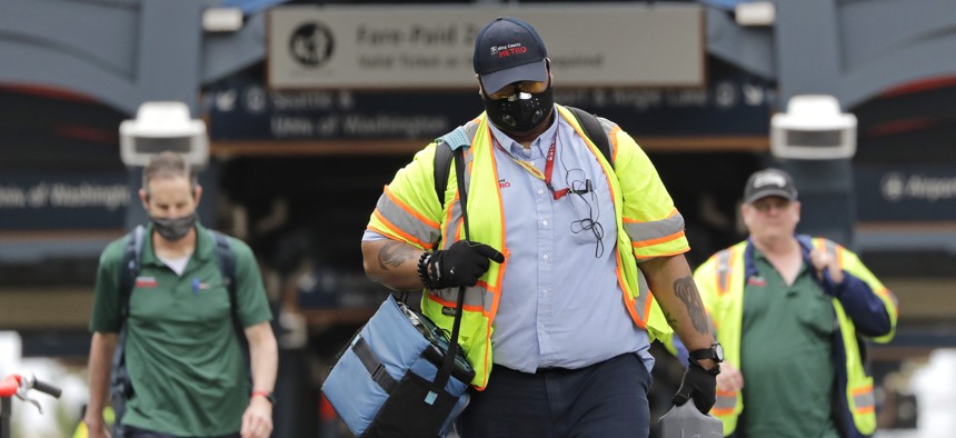 King County Metro bus workers walk off of a transit platform Monday, May 11, 2020, in Seattle. 