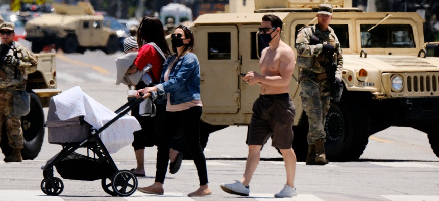A woman pushes her baby stroller across a blocked street with National Guard in Santa Monica, Calif. on June 7, 2020. Troops had been deployed to California cities to help with the response to protests against police brutality. 