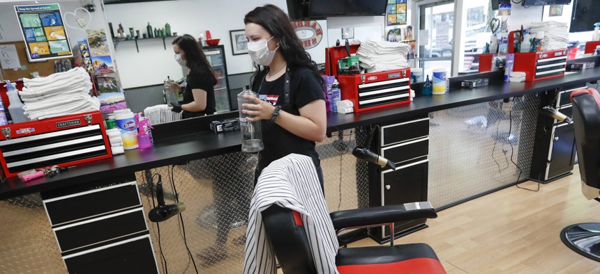 A stylist arranges items in her workspace Thursday, June 4, 2020, as she prepares for her first day back on the job at the West View Barber Shop ahead of Pennsylvania's loosening of Covid-19 restrictions.