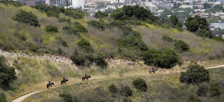 Riders on horseback advance down recently reopened hiking trails inside Griffith Park on May 14, 2020 in Los Angeles.