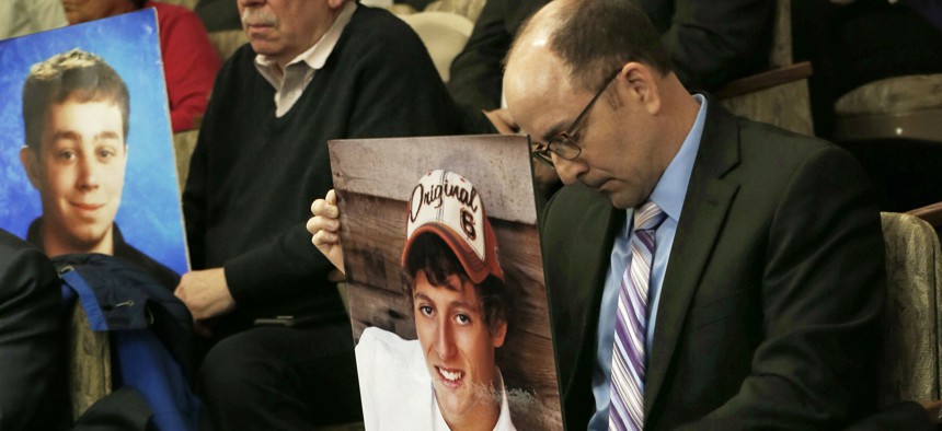 Greg LaVallee, right, testifies at a legislative hearing in Minnesota last year, holding a photo of his son, who was killed by a driver who was using a cellphone. 