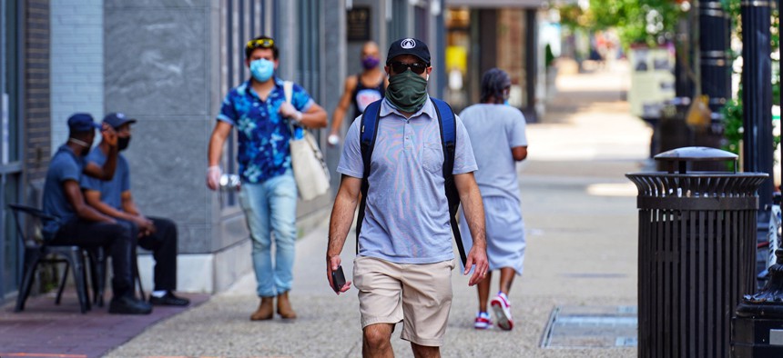 People in Washington, D.C. walk with masks on.
