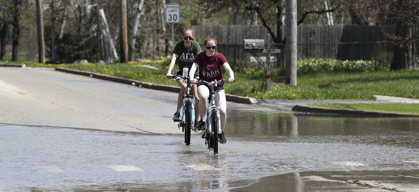 People ride bicycles on a flooded road in Waukegan, Illinois, north of Chicago. 