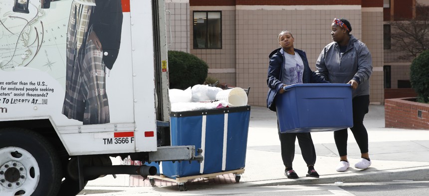 Howard University students Ayana Sallee, left, of Chesapeake, Va., and Jennifer Nnadozie, of Atlanta, load belongings into a U-Haul truck as they move out of their dorm in Washington, Wednesday, March 18, 2020.