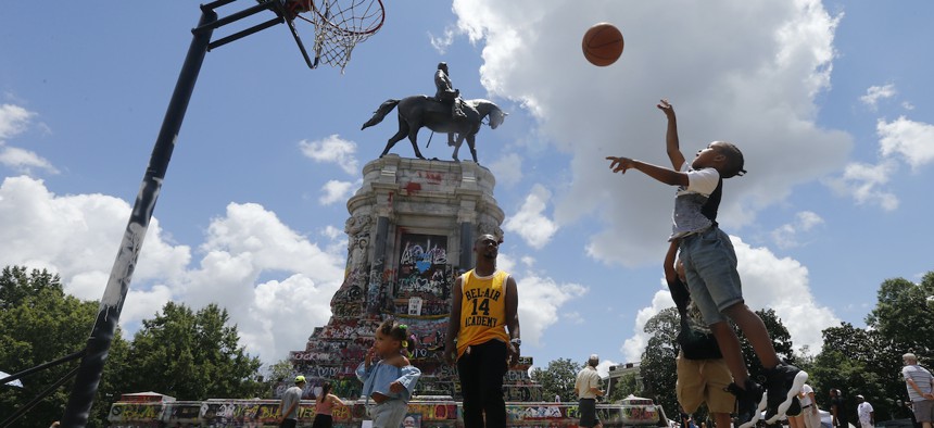 Isaiah Bowen, right, takes a shot as his dad, Garth Bowen, center, looks on at a basketball hoop in front of the statue of Confederate General Robert E. Lee on Monument Avenue Sunday June 21, 2020, in Richmond, Va.