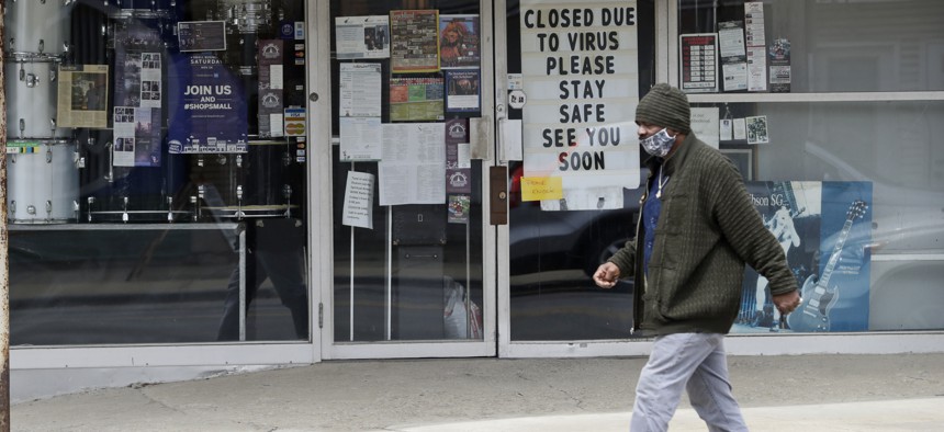 A man wearing a mask walks past "The Music Emporium," during the coronavirus pandemic on May 6, 2020, in Cleveland.