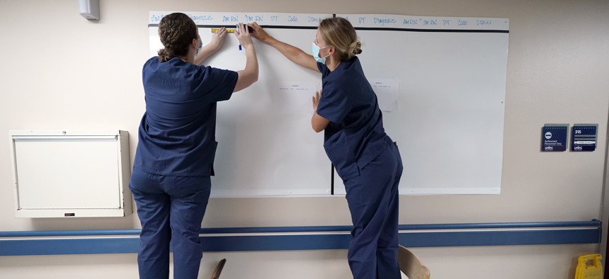 Registered nurses Army Capt. Rachel Curtis, right, and Capt. Christa Angelotti, with the Urban Augmentation Medical Task Force, sets up a patient board inside a wing at United Memorial Medical Center, Thursday, July 16, 2020, in Houston. 