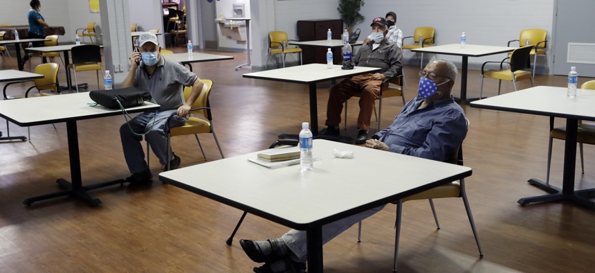 A group of men sit with socialdistincing inside an air conditioned room at a cooling center as temperatures rise amid the COVID-19 pandemic Wednesday, May 6, 2020, in Los Angeles. 