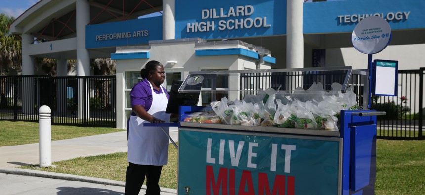 A cafeteria worker pushes a cart full of food to distribute a free lunch to the students and community at Dillard High School amid the coronavirus outbreak and school closings on March 16, 2020, in Fort Lauderdale, Fla. 