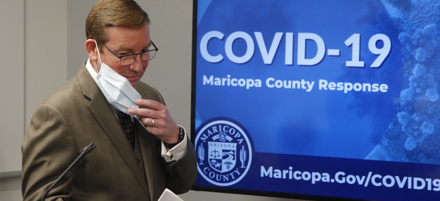 Robert Rowley, director of the Maricopa County Emergency Management Department, removes his face covering as he prepares to speak at a July 16 press conference.