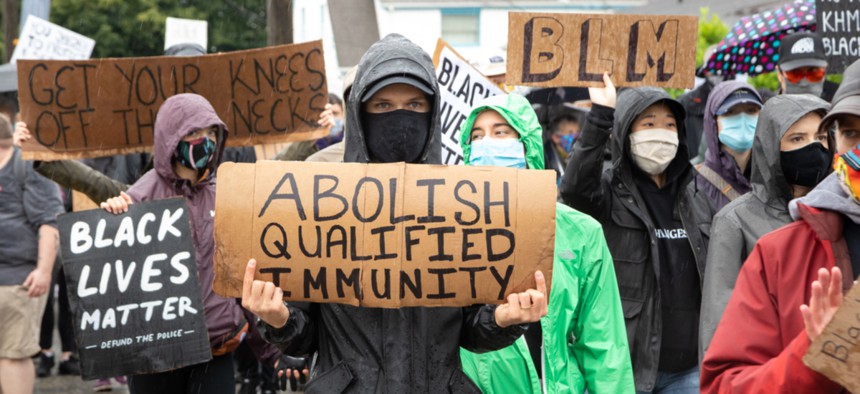 A protester in Washington holds a sign calling for the end of qualified immunity.
