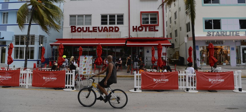 People are seen on Ocean Drive as Miami Dade County is mandating a daily 8 p.m. to 6 a.m. curfew.