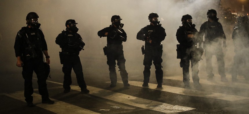Federal officers are surrounded by smoke as they push back demonstrators during a Black Lives Matter protest at the Mark O. Hatfield United States Courthouse Wednesday, July 29, 2020, in Portland, Ore. 