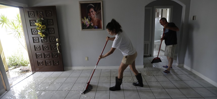 Michelle Garcia, left, and her father Martin, right, sweep water from their home, Monday, July 27, 2020, in Weslaco,Texas. The Garcia's home was flooded by Hurricane Hanna as it passed through the area dropping heavy rains which caused flooding. 
