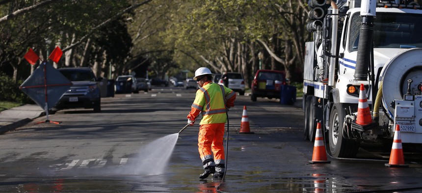 A city utility worker washes down a street in Sacramento, California in March 2020.