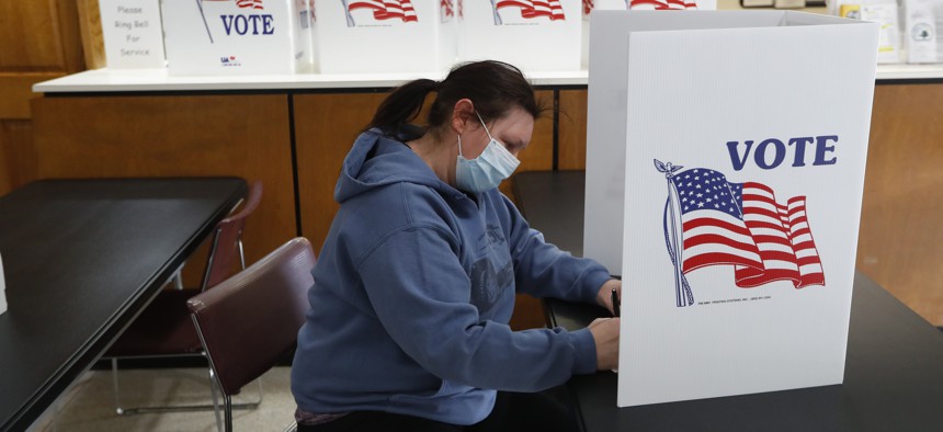 In this Tuesday, May 5, 2020 file photo, a voter fills out an absentee ballot at City Hall in Garden City, Mich., as about 50 Michigan communities participate in largely mail-based local elections.