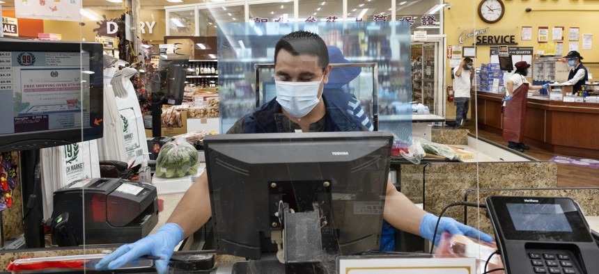 A grocery store worker checks out customers in Los Angeles.