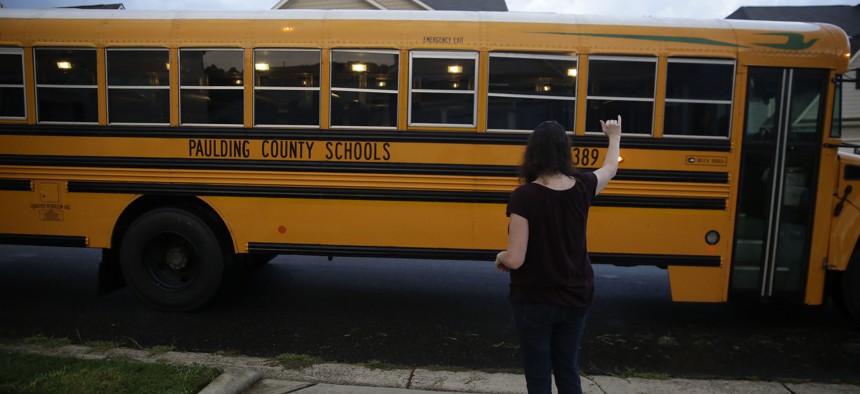 A mom waves goodbye to a school bus on Aug. 3 in Dallas, Ga.