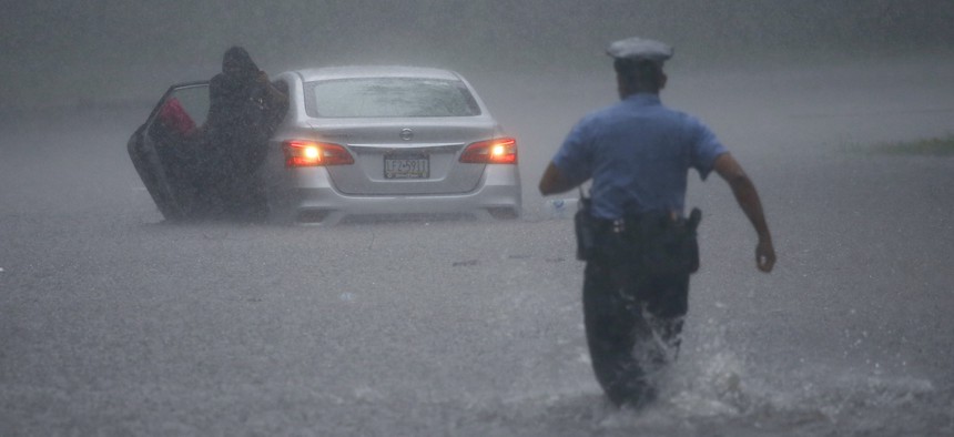 A police officer rushes to help a stranded motorist during Tropical Storm Isaias, Tuesday, Aug. 4, 2020, in Philadelphia. The storm spawned tornadoes and dumped rain during an inland march up the East Coast after making landfall as a hurricane.