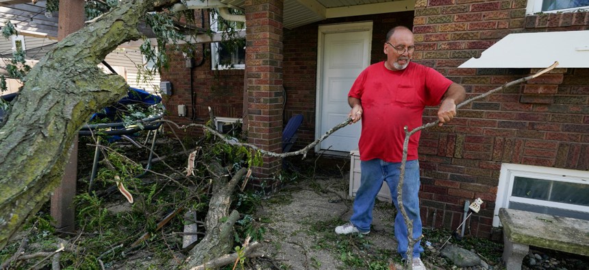 Cecil Gott removes a fallen tree that rests on the back of a neighbor's home, Friday, Aug. 14, 2020, in Cedar Rapids, Iowa.