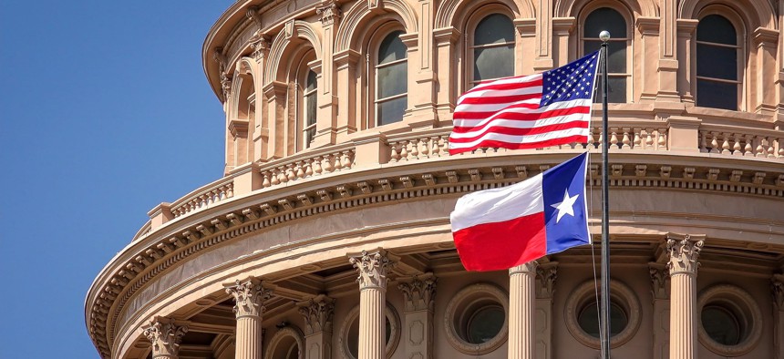 The American flag and Texas state flag fly outside the Texas state Capitol building in Austin.
