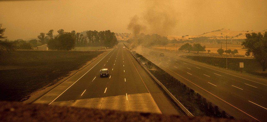 A police vehicle drives along Interstate 80, which was closed when flames from the LNU Lightning Complex fires jumped the roadway, in Vacaville, Calif., on Wednesday, Aug. 19, 2020. 