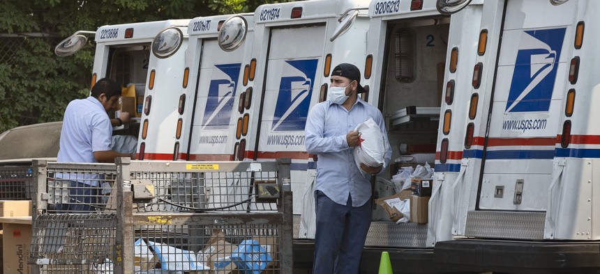 Postal workers load packages in their mail delivery vehicles at the Panorama city post office on Aug. 20, 2020 in the Panorama City section of Los Angeles. 