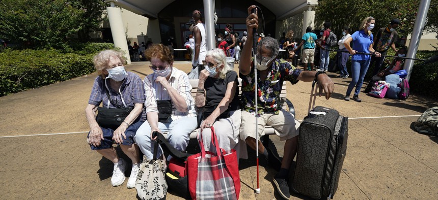 Evacuees wait to board a bus as they evacuate, Tuesday, Aug. 25, 2020, in Galveston, Texas. They are being taken to Austin, Texas, ahead of Hurricane Laura.