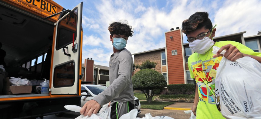 Amid concerns of the spread of COVID-19, brothers Brian, left, and David Rayo wear masks as they pick up school lunches for themselves and other siblings at their apartment complex in Dallas, Tuesday, May 5, 2020.
