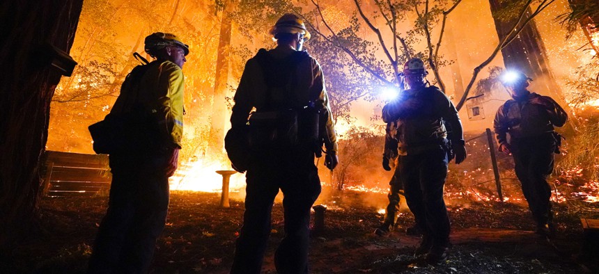 Firefighters make a stand in the backyard of a home in front of the advancing CZU August Lightning Complex Fire on Aug. 21, 2020, in Boulder Creek, Calif.