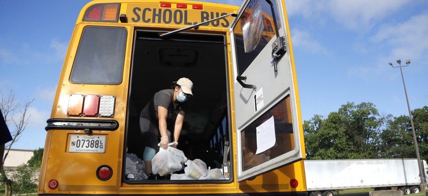 A bus driver with the Montgomery County School District helps load a bus with bags of food to be donated to residents, Friday, July 10, 2020, in Derwood, Md. 