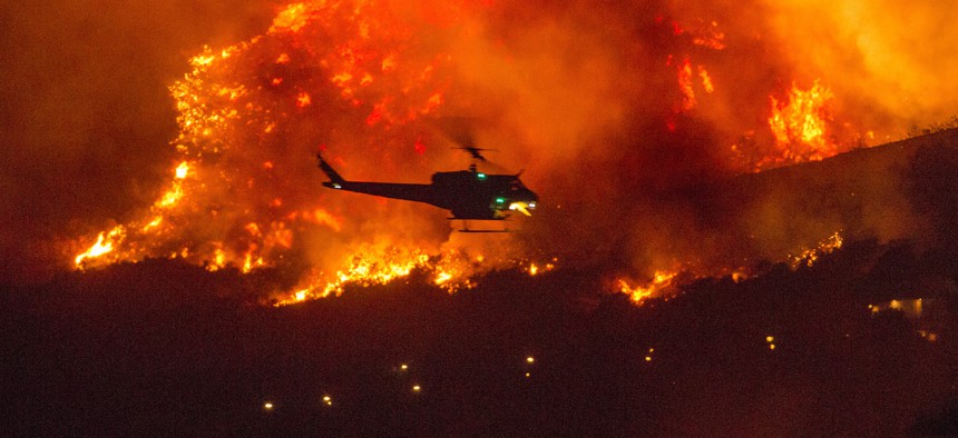 In this Saturday, Sept. 5, 2020, photo, a helicopter prepares to drop water at a wildfire in Yucaipa, Calif. 
