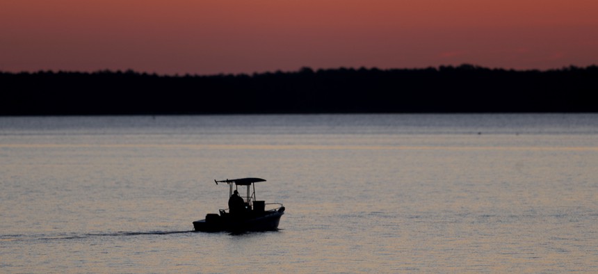 In this May 14, 2020 photo, a small boat chugs along the Honga River near the Chesapeake Bay as the sky lights up at sunrise, in Fishing Creek, Md.