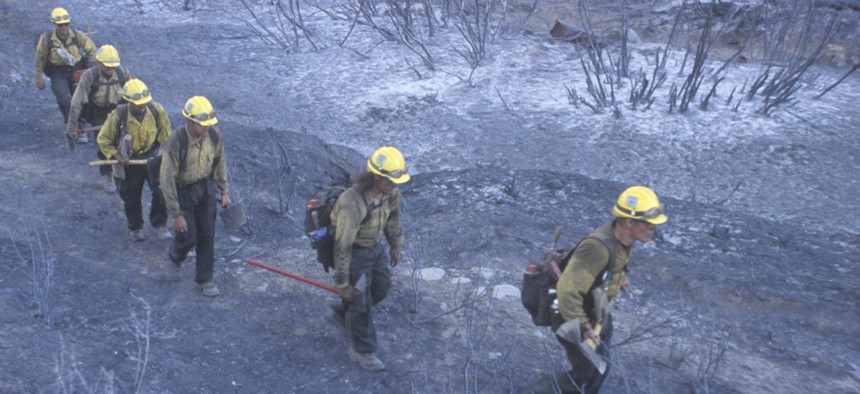 Firefighters in California walk through an area ravaged by wildfires.