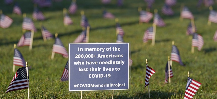 Activists from the COVID Memorial Project mark the deaths of 200,000 lives lost in the U.S. to COVID-19 after placing thousands of small American flags places on the grounds of the National Mall in Washington, Tuesday, Sept. 22, 2020. 