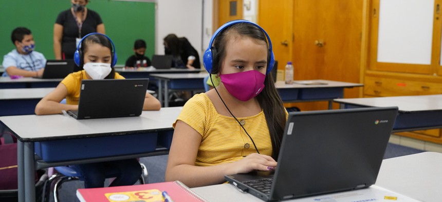 Reyna Najera, front, and her sister, Brenda, work on a laptops in a classroom in Newlon Elementary School on Aug. 25, 2020, which is one of 55 Discovery Link sites set up by Denver Public Schools for students to do remote learning.