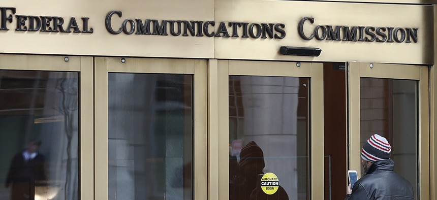 In this Thursday, Dec. 14, 2017, file photo, a person with a smartphone enters the Federal Communications Commission building in Washington.